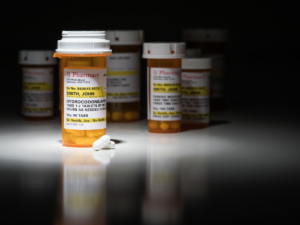 Numerous prescription bottles under spotlight.