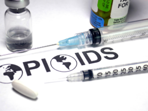 Word "opioid" is spelt on paper with the globe as the O. Needles are next to the word.