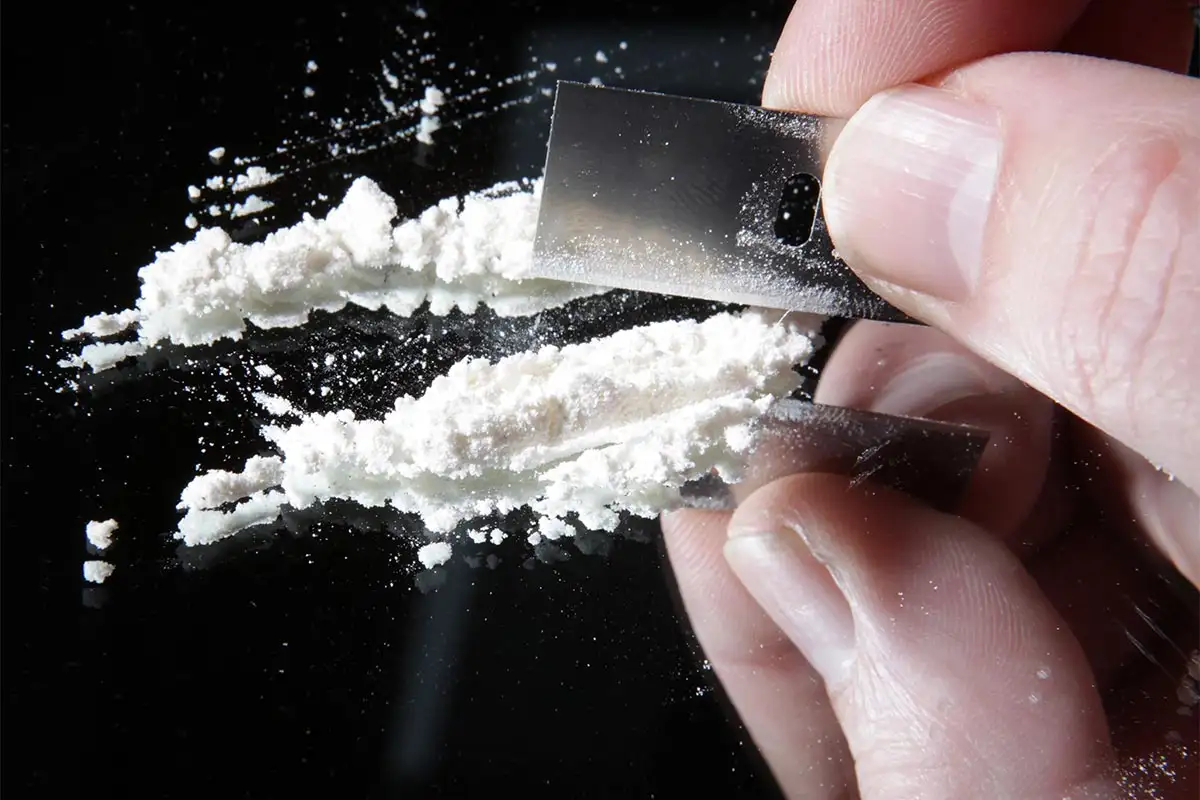 cocaine-or-other-drugs-cut-with-razor-blade-on-mirror.-hand-dividing-white-powder-narcotic