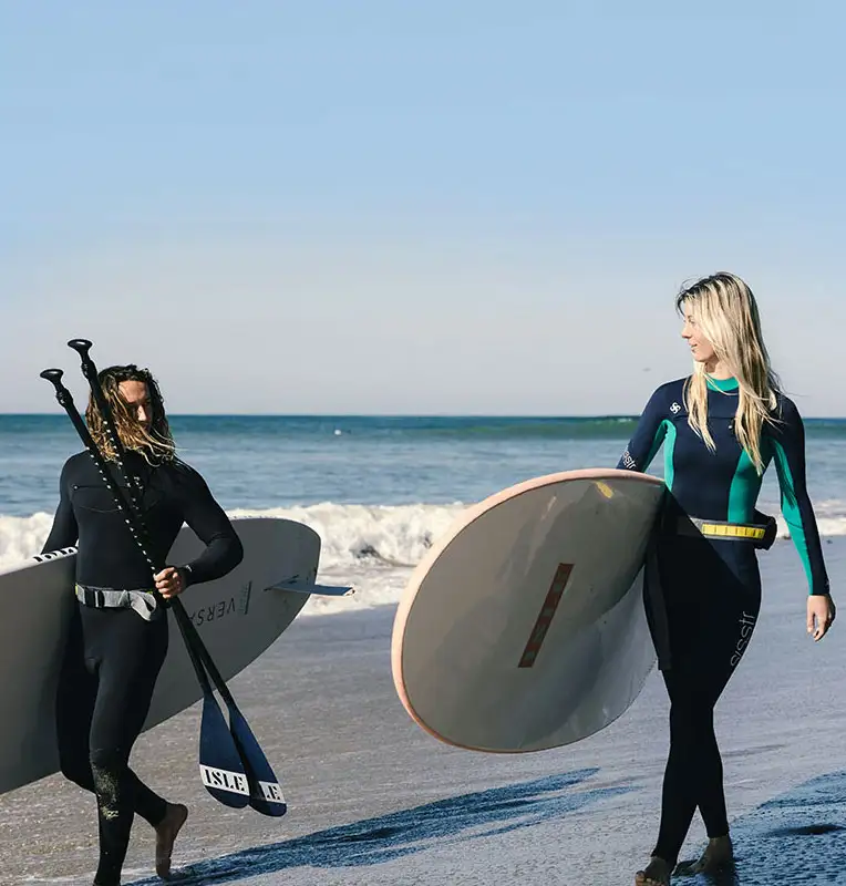 male and female clients carrying their surf boards in newport beach CA