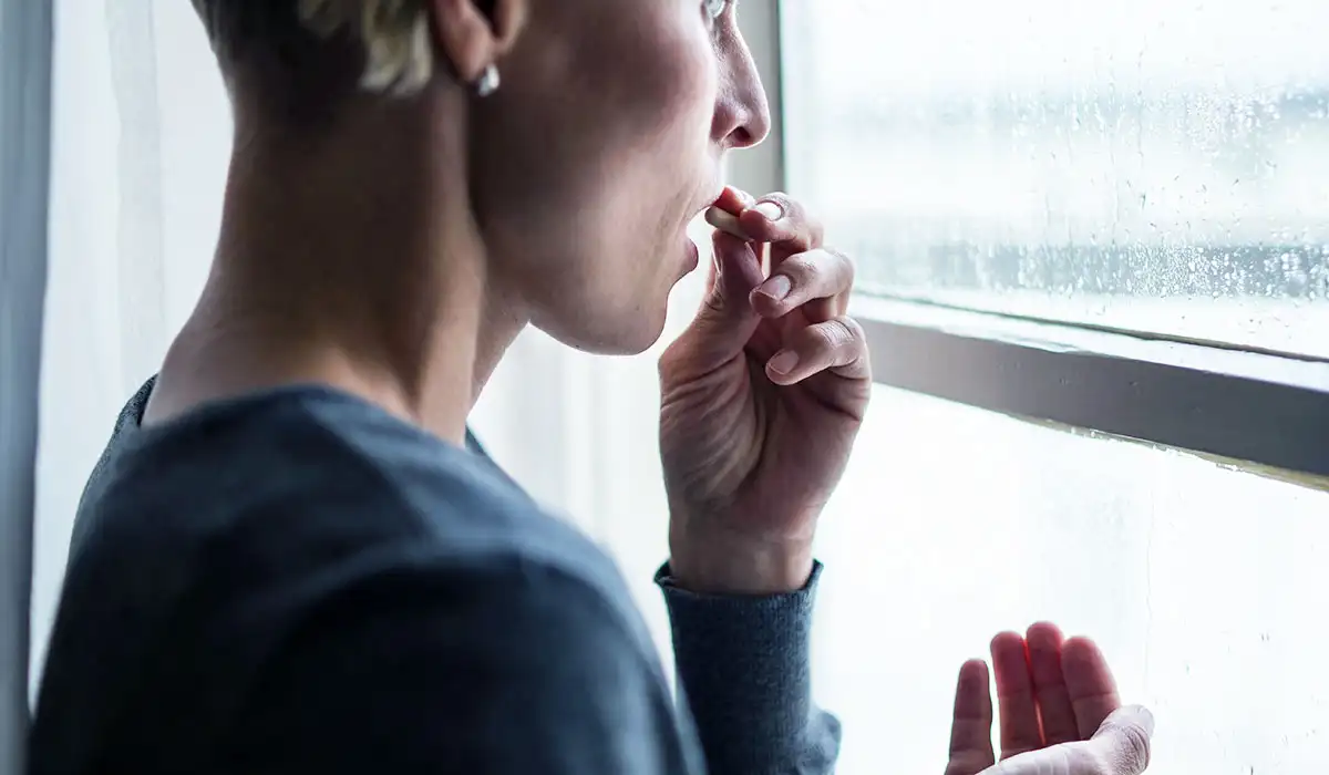 Xanax Addiction Treatment woman with xanax addiction facing outside the window taking xanax pills 1