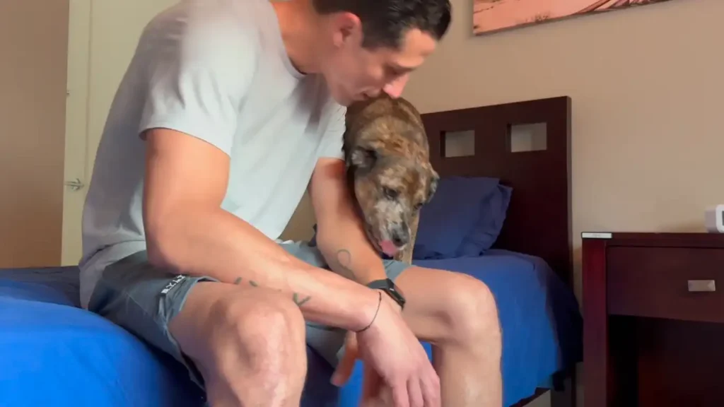 man sitting on his bed being comforted by his dog showing the benefits of pet friendly rehab