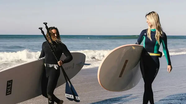 male and female clients carrying their surf boards in newport beach CA