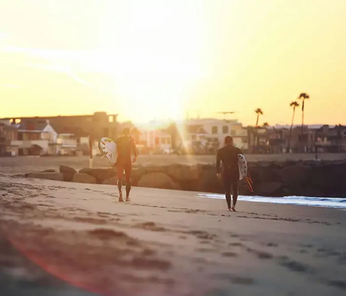 two male clients surfing in newport beach california as part of their addiction treatment