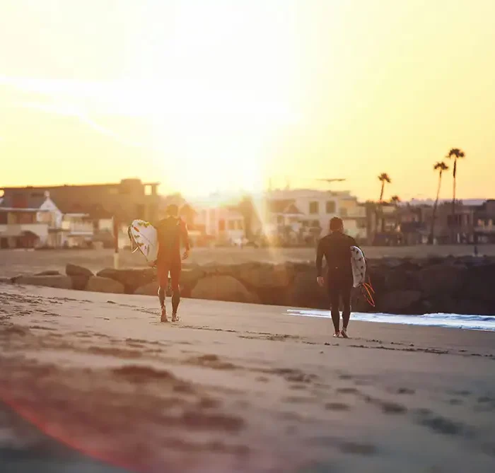 two male clients surfing in newport beach california as part of their addiction treatment